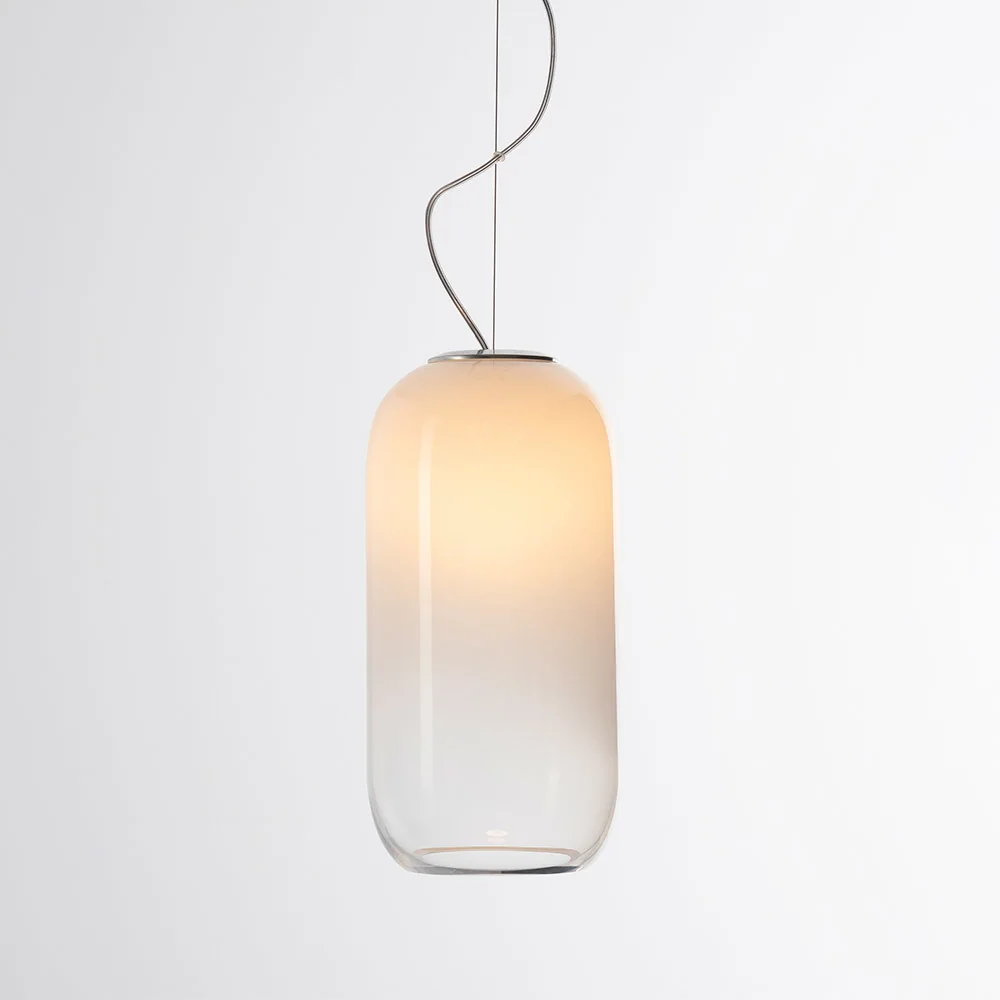 Artemide: Länglicher, unten abgerundeter Schirm mit hellem Farbverlauf, an einem dünnen Kabel aufgehängt.