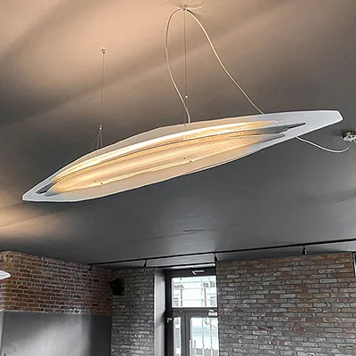 Ayal Rosin: Flache elliptische Pendelleuchte mit heller Unterseite unter einer grauen Decke.