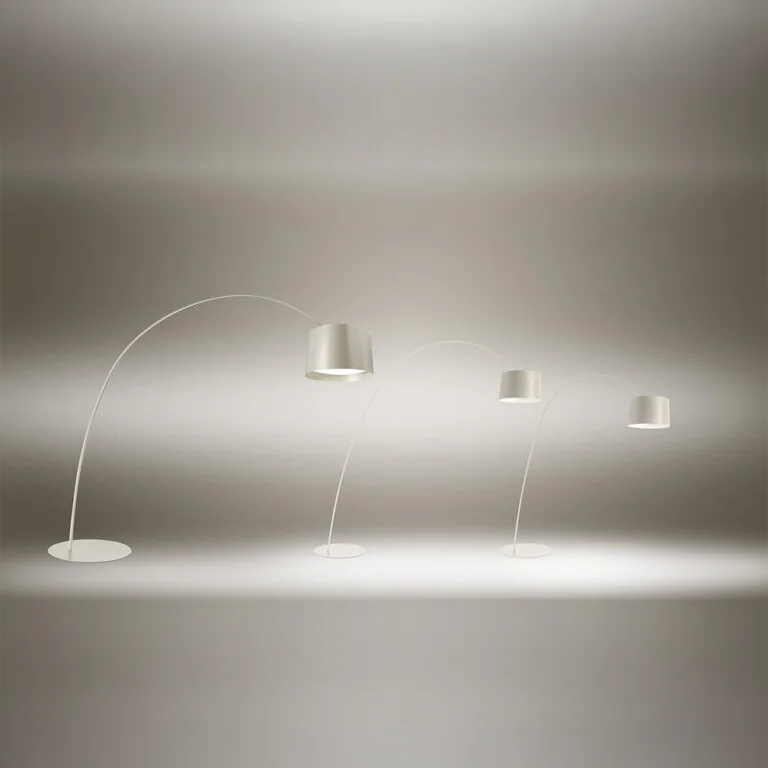 Foscarini: Gruppe heller Boden- und Hängevarianten vor grauem Hintergrund, darunter eine weit auskragende Bogenleuchte.