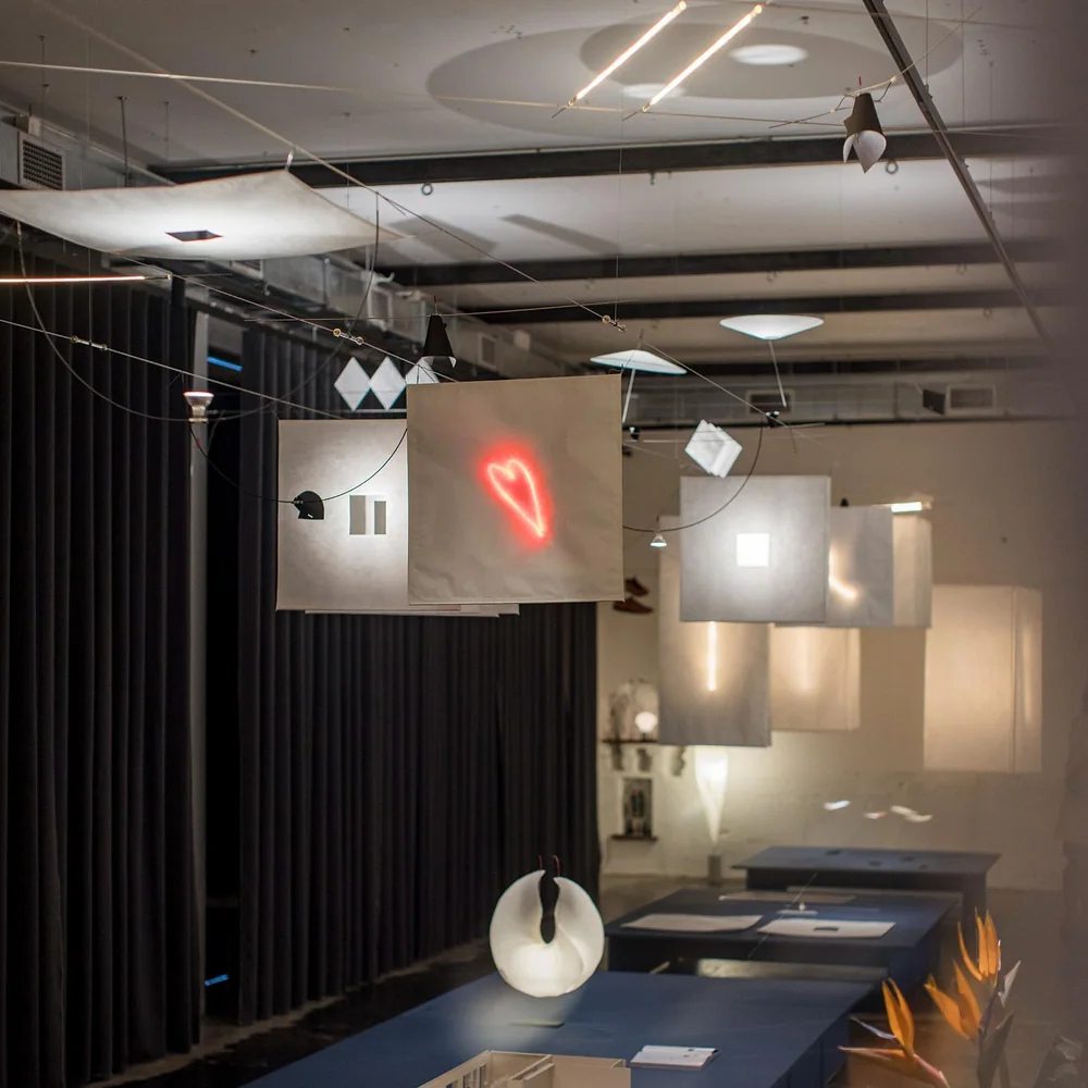 Ingo Maurer: Ausstellungsraum mit gespannten Seilen, kleinen Leuchten und mehreren inszenierten Objekten.