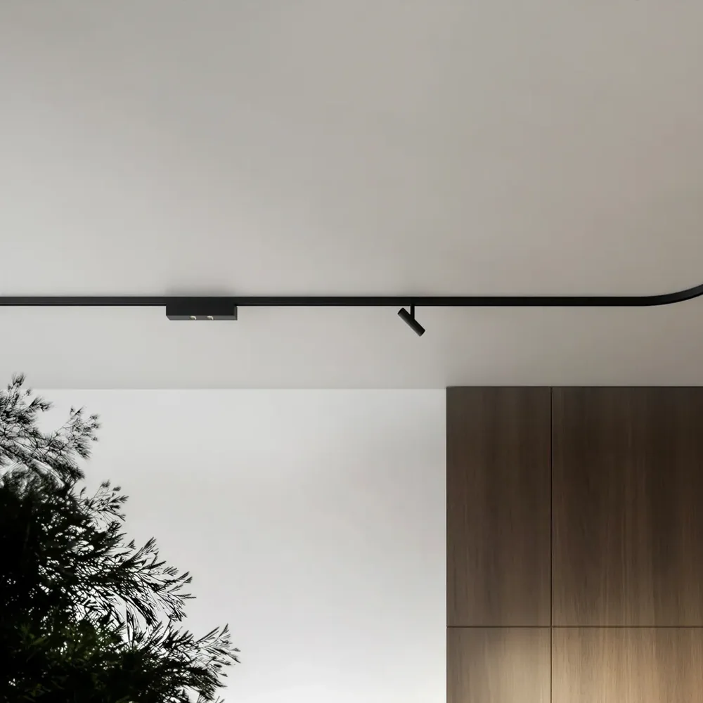 Kreon: Schwarze schmale Schiene mit gerundeter Ecke und kleinen Strahlern an einer hellen Decke.