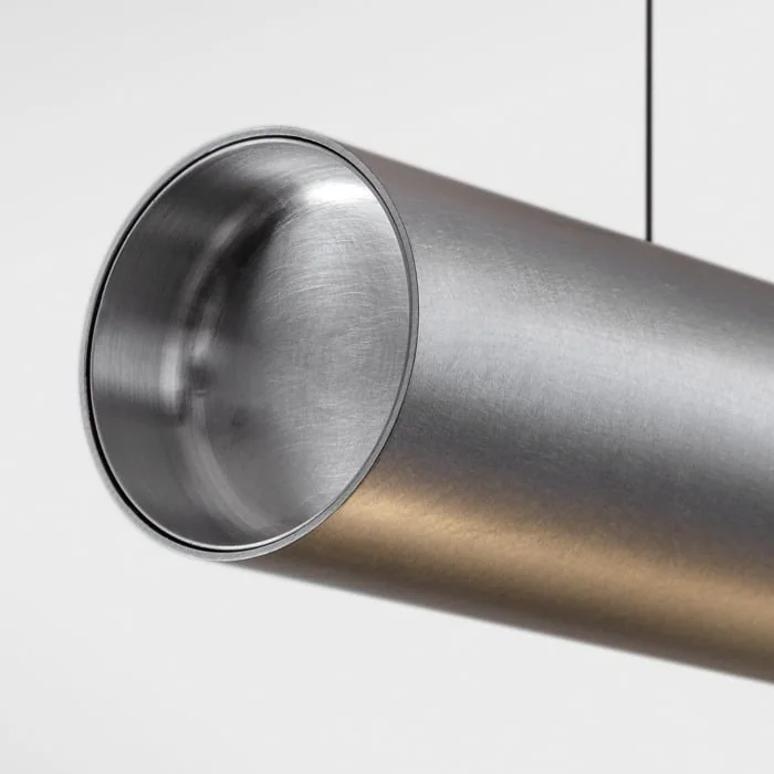 Modular Lighting Instruments: Engerer vertikaler Ausschnitt einer röhrenförmigen Leuchte mit sanft reflektierender Oberfläche.