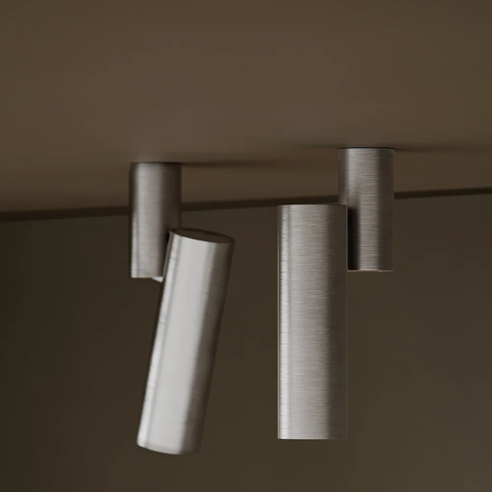 Modular Lighting Instruments: Mehrere zylindrische Strahler an einer hellen Decke, teilweise schräg ausgerichtet.