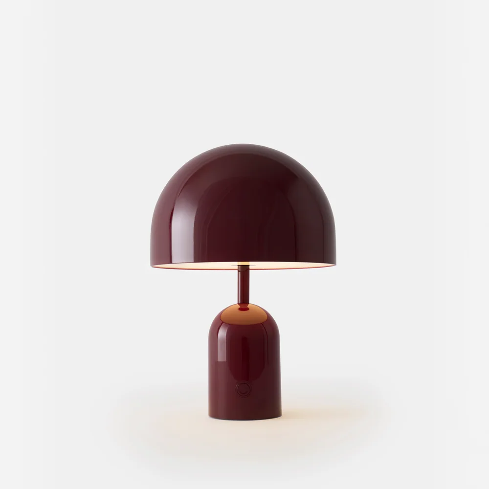 Tom Dixon: Kleine tragbare Leuchte mit breitem kuppelförmigem Schirm und rundem Fuß vor weißem Hintergrund.